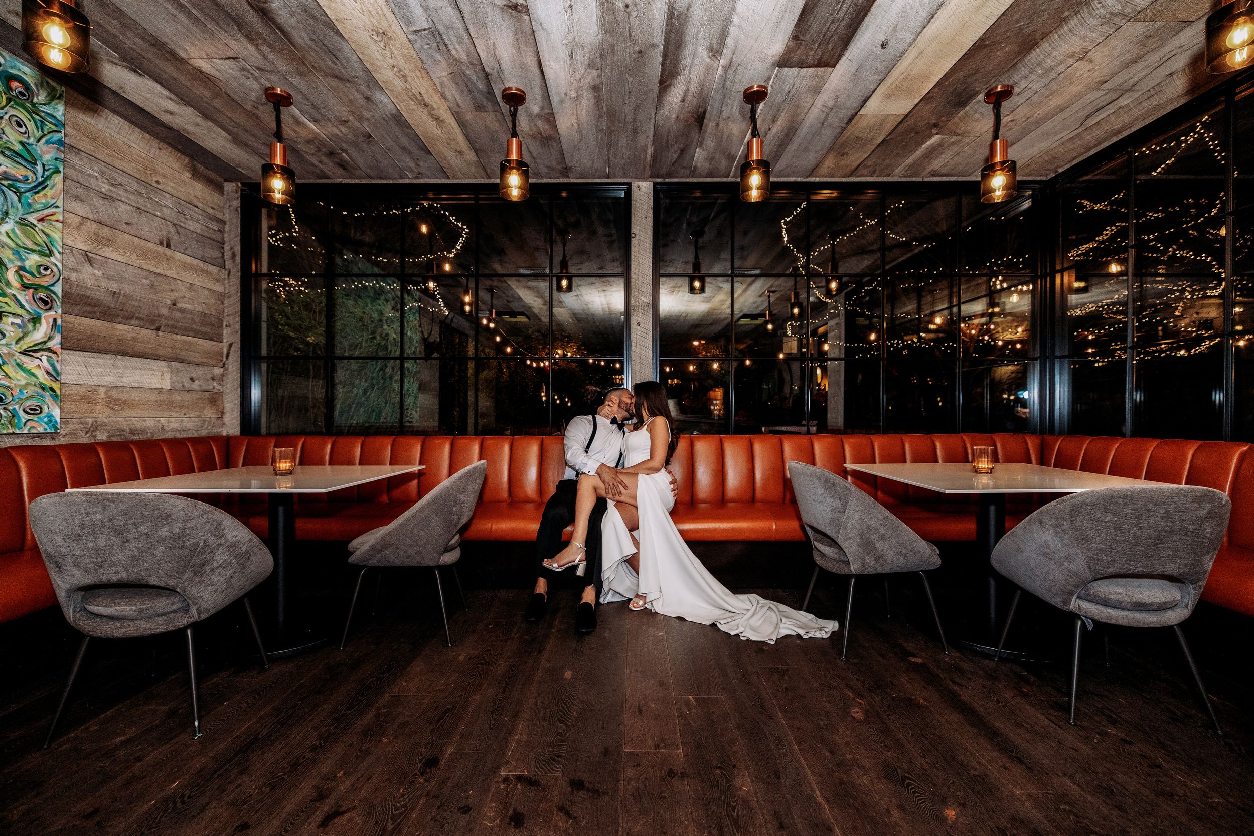Wedding venue interior with rustic wooden ceiling beams and warm pendant lighting.