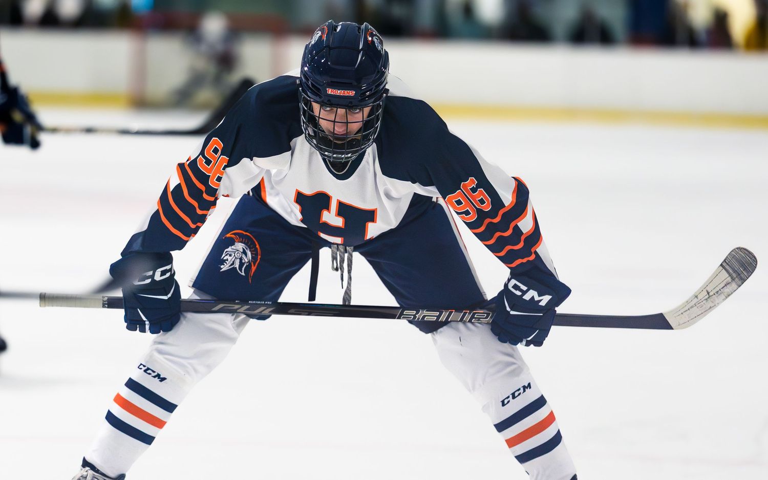 High school hockey player in navy/white Hershey Trojans jersey, focused on ice, action shot by SportsFox Photography