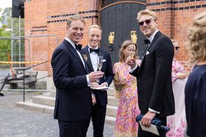 Bryllupsgjester utenfor Høvik kirke. Smiler til kamera og skåler.