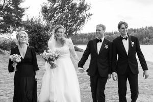 Sort-hvitt bilde av brudepar og forlovere som går mot kamera. Bak dem er havet.