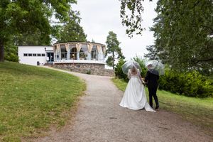 Brudepar med gjennomsiktige paraplyer går mot Hvalstrand bad og bryllupsfeiring.