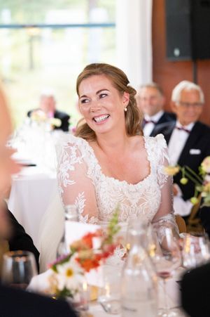 Nærbilde av brud som ser mot hennes høyre og smiler. Ler av noe som blir sagt i en tale.