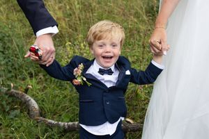 Brudeparets sønn som holder hånda til både mamma og pappa. Smiler, ler og ser rett i kamera.