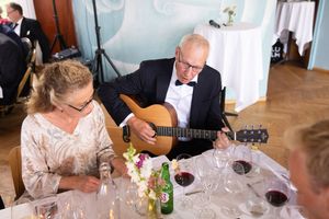 Brudgommens far som spiller gitar og ser ned på teksten som synges.