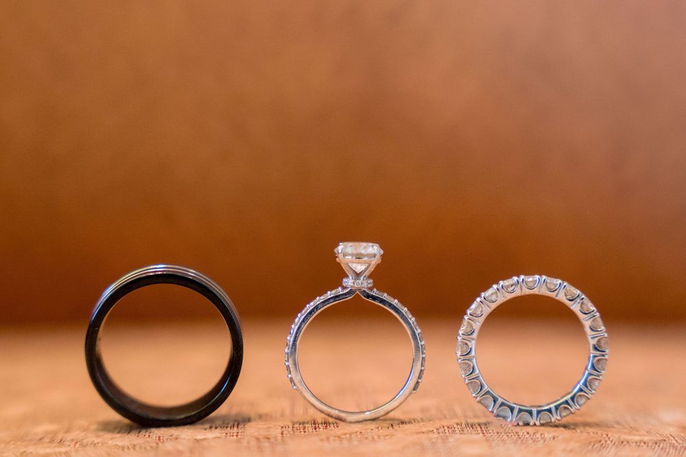Three elegant diamond engagement rings and wedding bands arranged in a row on a warm brown leather surface.