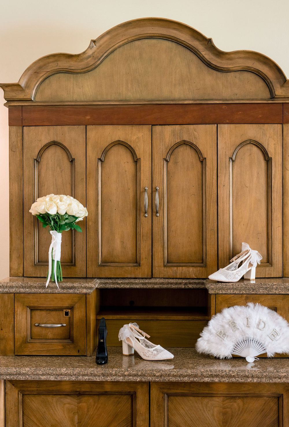 Wedding accessories including white shoes, fan and bouquet displayed on vintage wooden church pews in sequence.