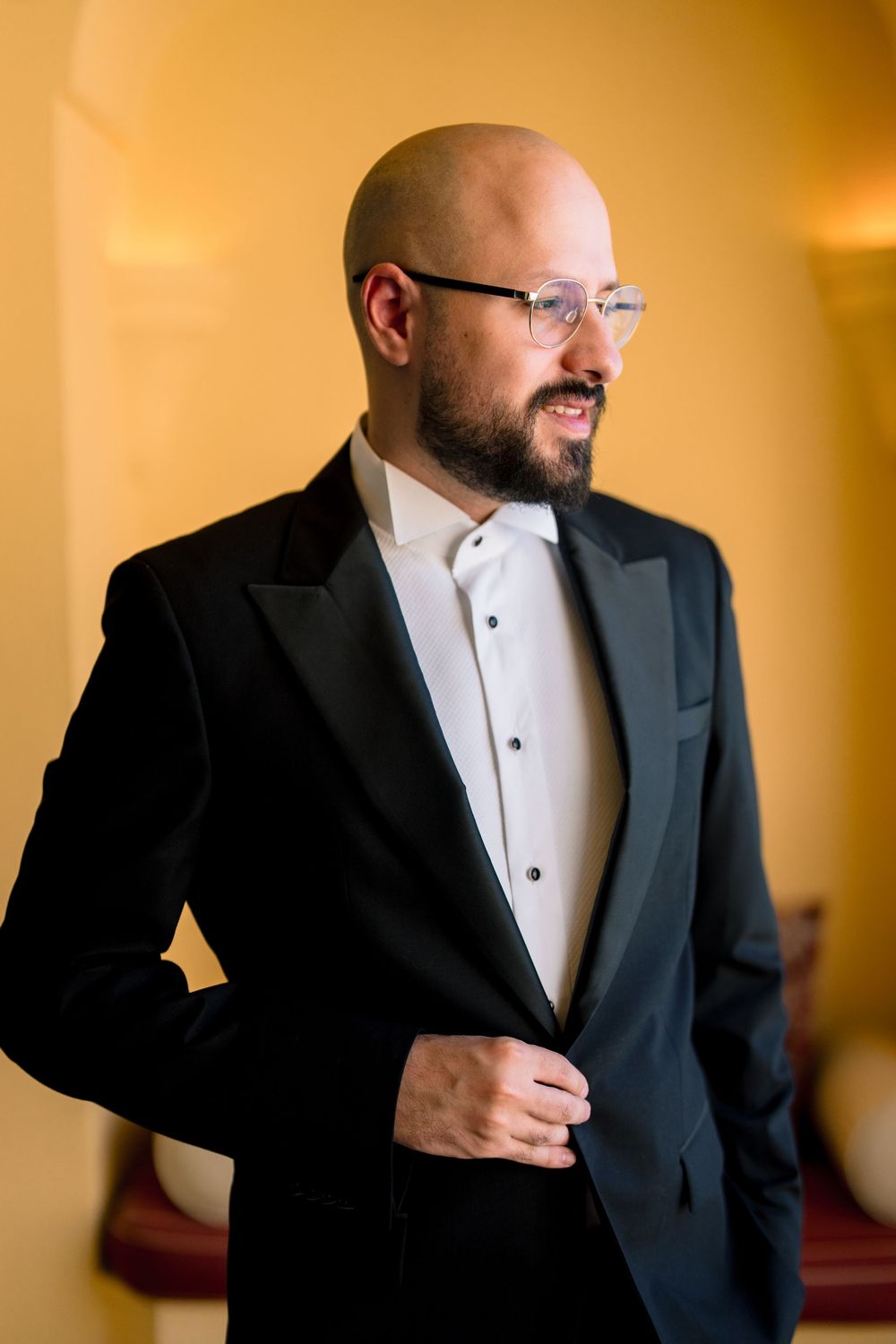 Man in black suit jacket and white dress shirt adjusts his tie in a sequence of formal portraits.