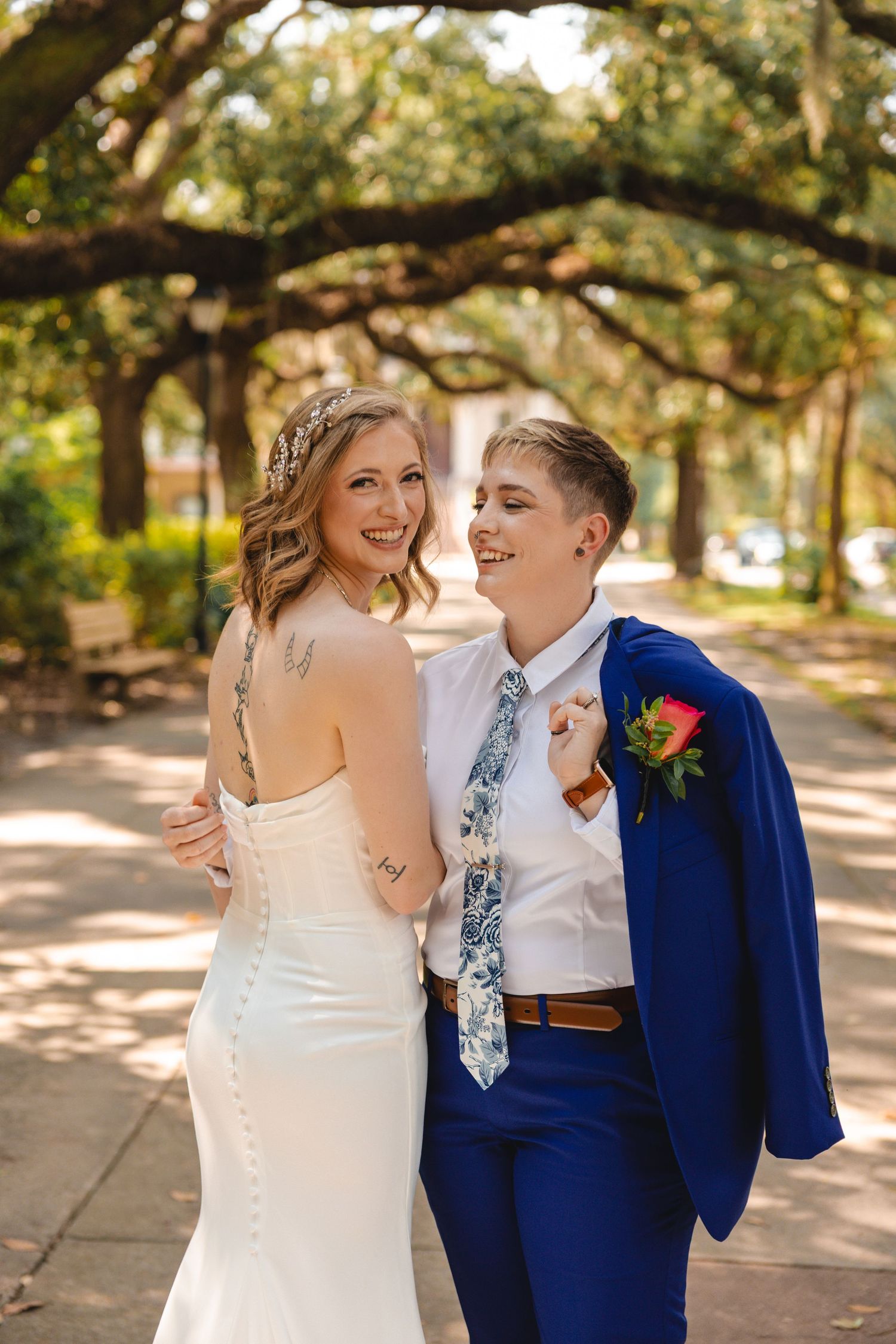 A happy couple shares intimate moments under oak trees during their wedding photoshoot.