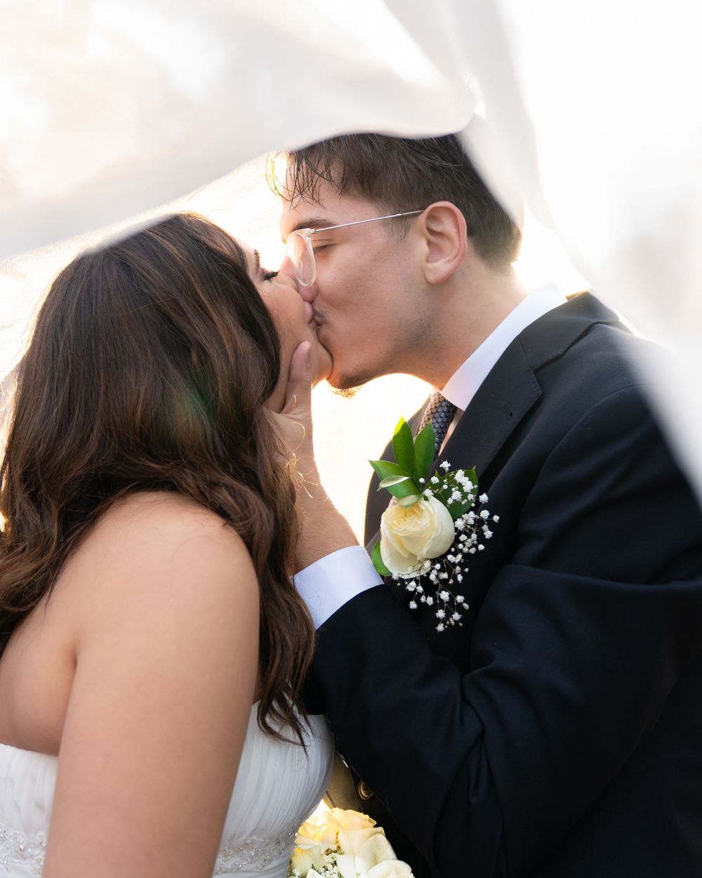 A tender moment captured between newlyweds with a white rose boutonniere.