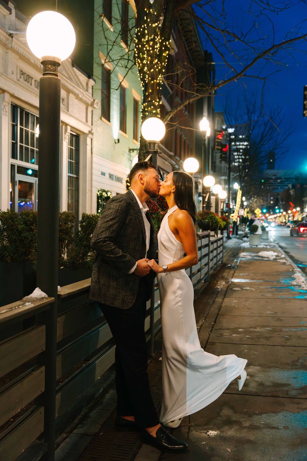 A romantic nighttime wedding portrait under glowing street lamps and city lights.