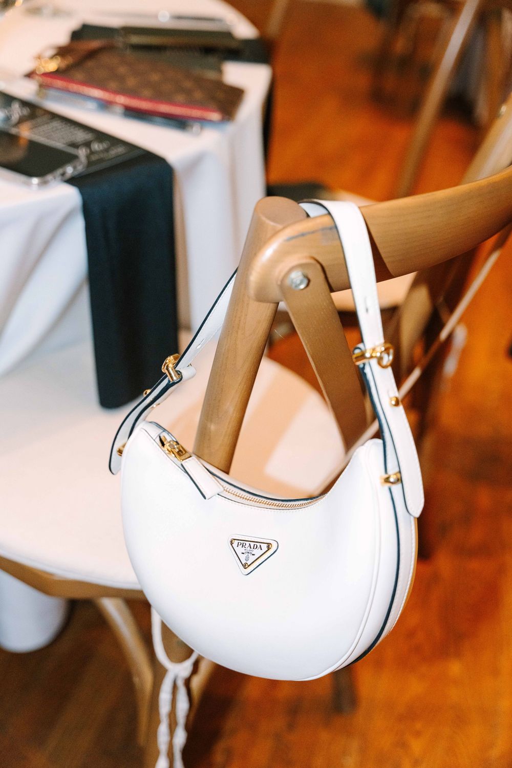 White designer high heel shoes with tan straps displayed on a wooden surface.