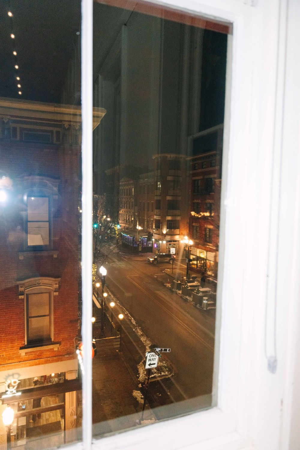 Nighttime cityscape view through large windows showing illuminated streets and buildings.