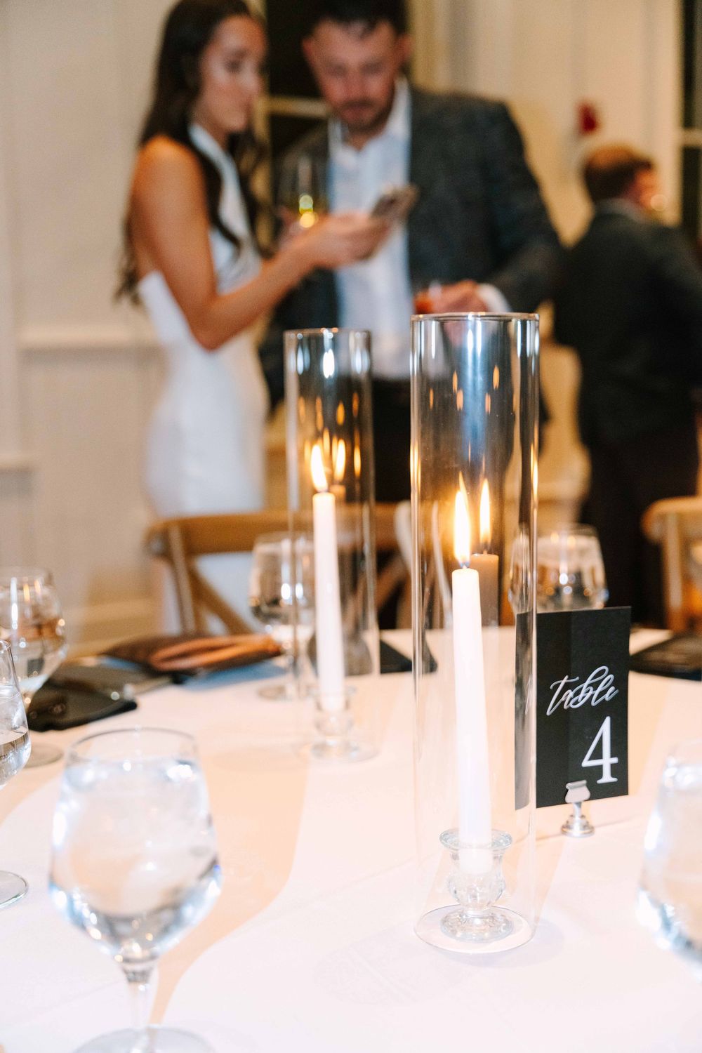 Elegant wedding reception table setting with candles and table numbers.