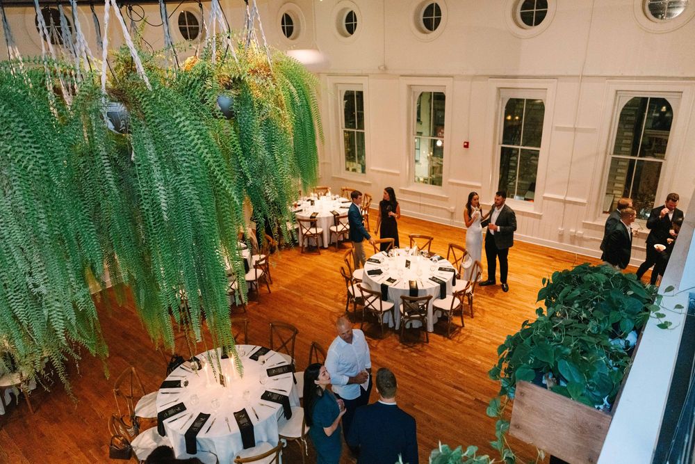 A wedding reception venue with elegant white tables and hanging greenery decor creates a romantic atmosphere.