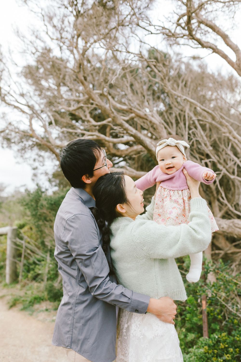 Joyful couple dancing and twirling together outdoors in a natural setting with trees and greenery.