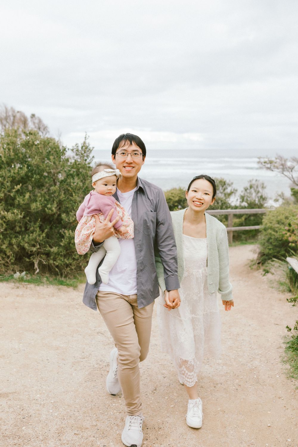 Family walking together on a sandy beach trail during an overcast day.