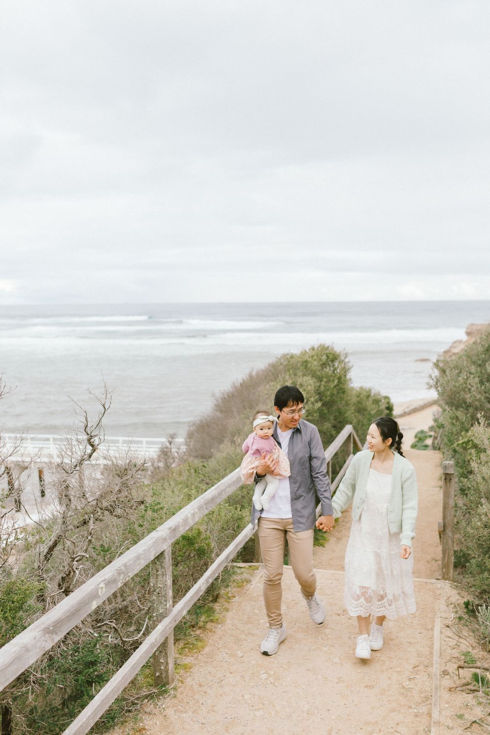 A group walks along a coastal path with ocean views on a cloudy day.
