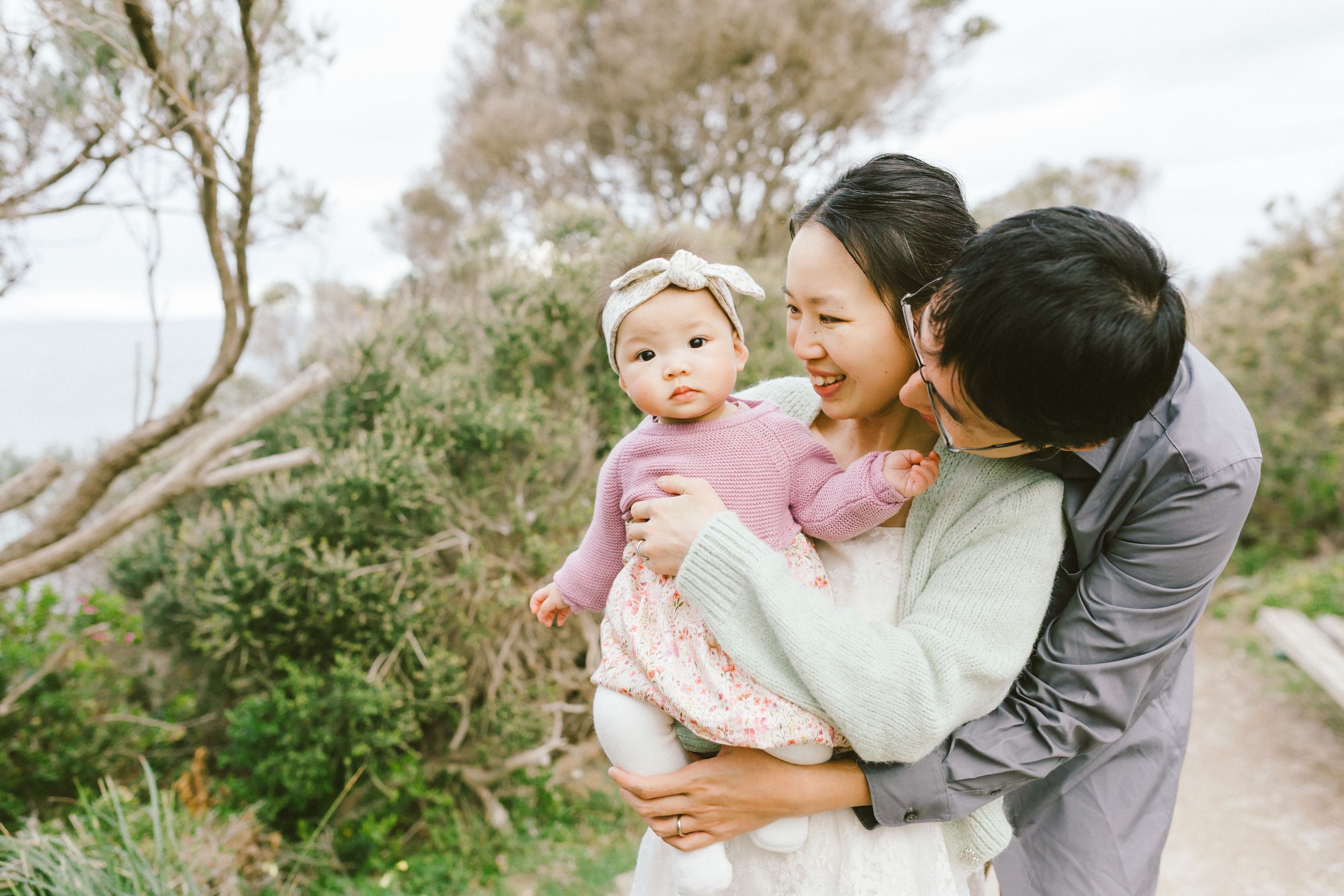 A sweet outdoor family moment captured in soft, natural lighting along a scenic pathway.