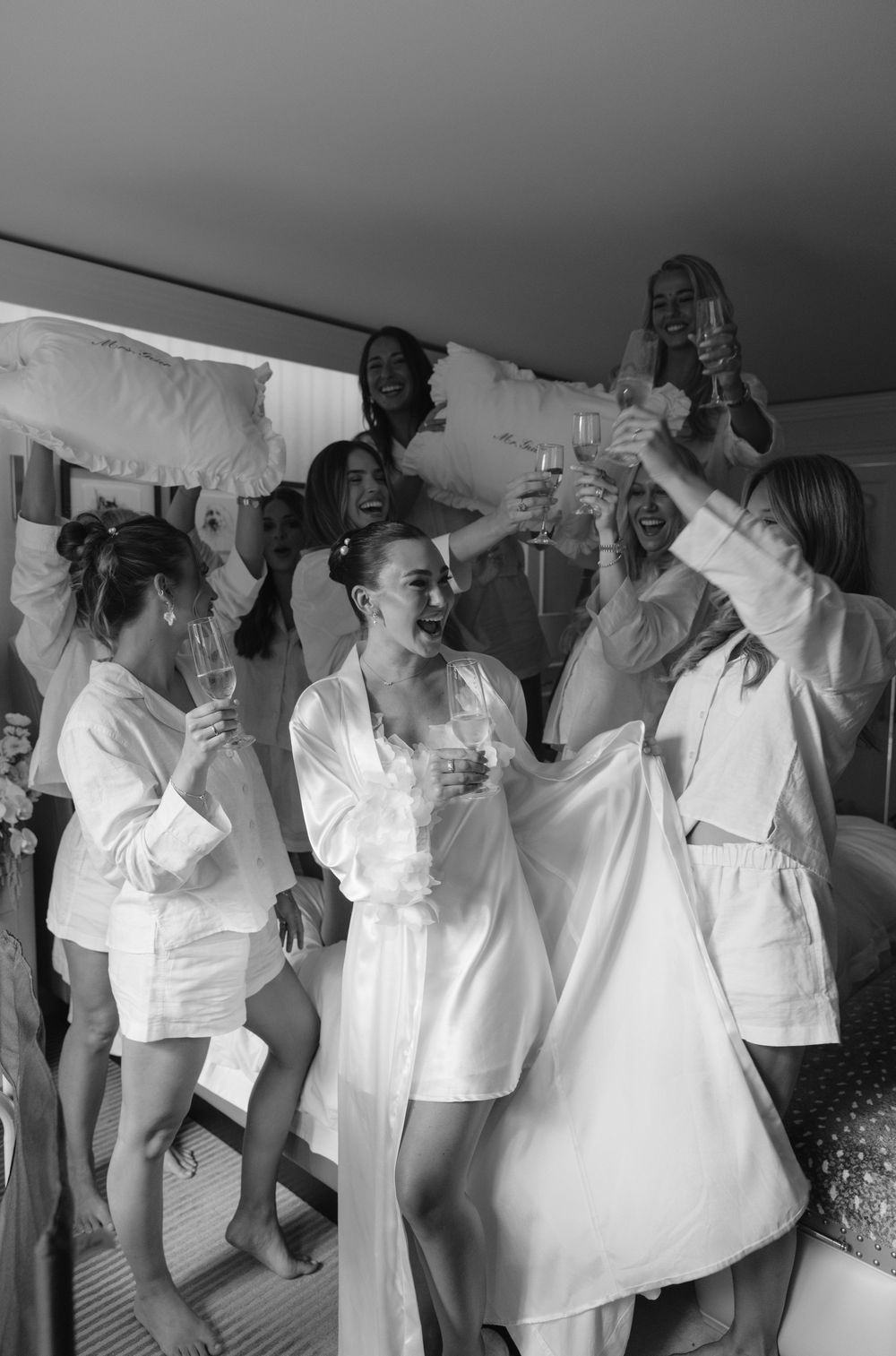 A group of people dressed in white outfits dance and celebrate together in a black and white photograph. Ritz-Carlton in Aspen, Colorado