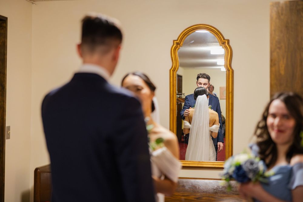 Bride and groom holding each other with reflection in the mirror