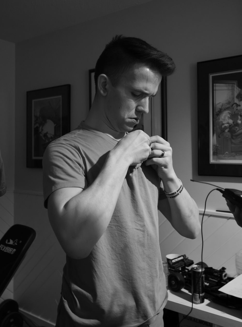 Person adjusting audio equipment in indoor setting with framed artwork in background.