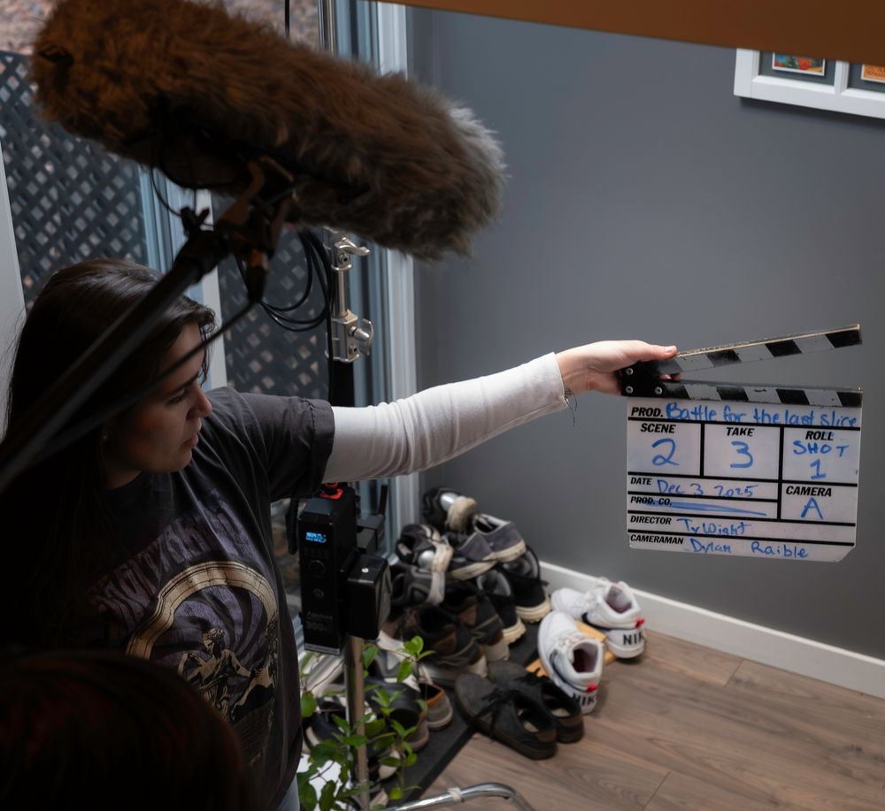 Film production crew working with equipment and clapperboard on wooden table.