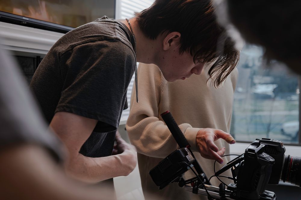 Film crew members working together to adjust camera equipment during a production shoot.