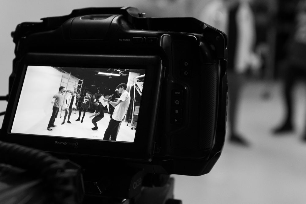 Behind-the-scenes video production setup with camera equipment and lighting in a studio space.