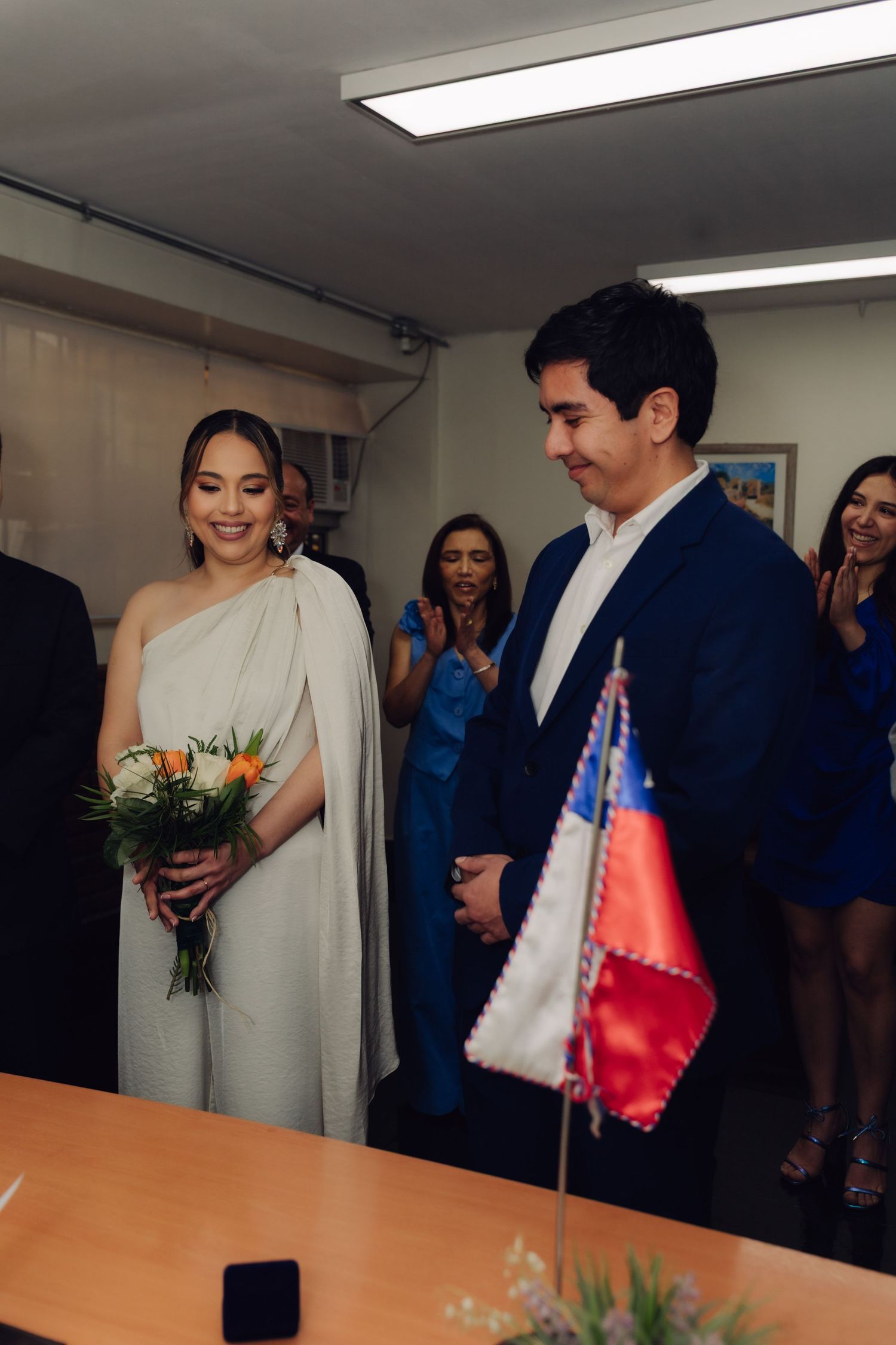 Smiling bride in white gown and groom in navy suit at civil wedding ceremony.