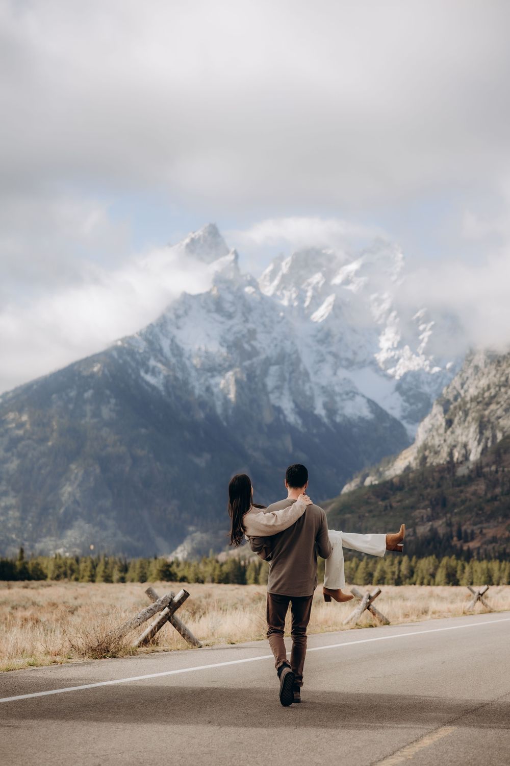 A sequence of images showing two people playfully running on an empty road with snow-capped mountains in the background.
