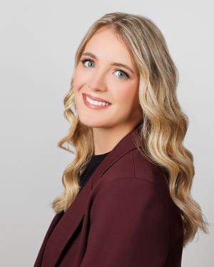 Professional studio photo featuring wavy blonde hair and a burgundy jacket with natural lighting.
