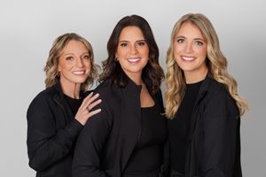 Four women wearing black tops smile together in a casual professional photo series.