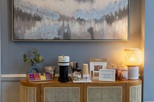 Modern living room features a long white credenza beneath abstract gray artwork with warm accent lighting and decorative items.