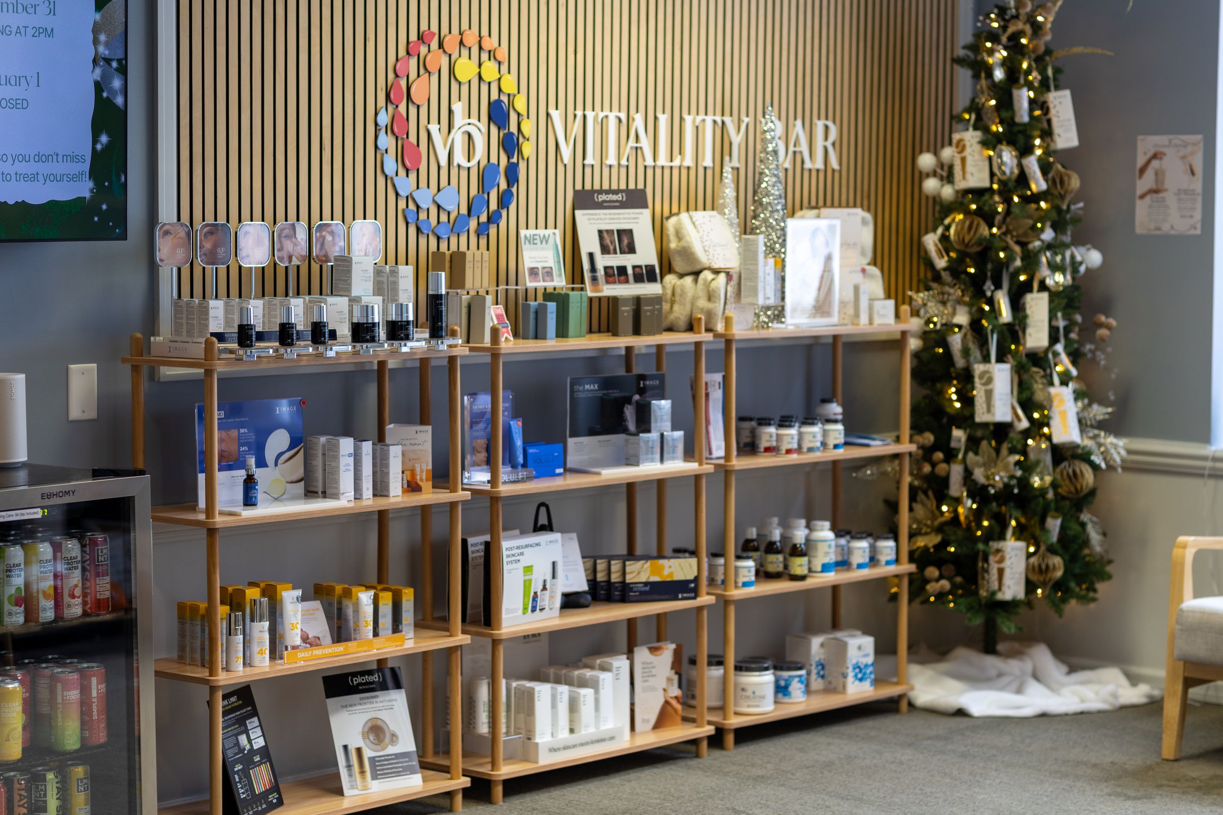 Modern spa interior with wooden shelving displaying luxury skincare and beauty products against gray walls.