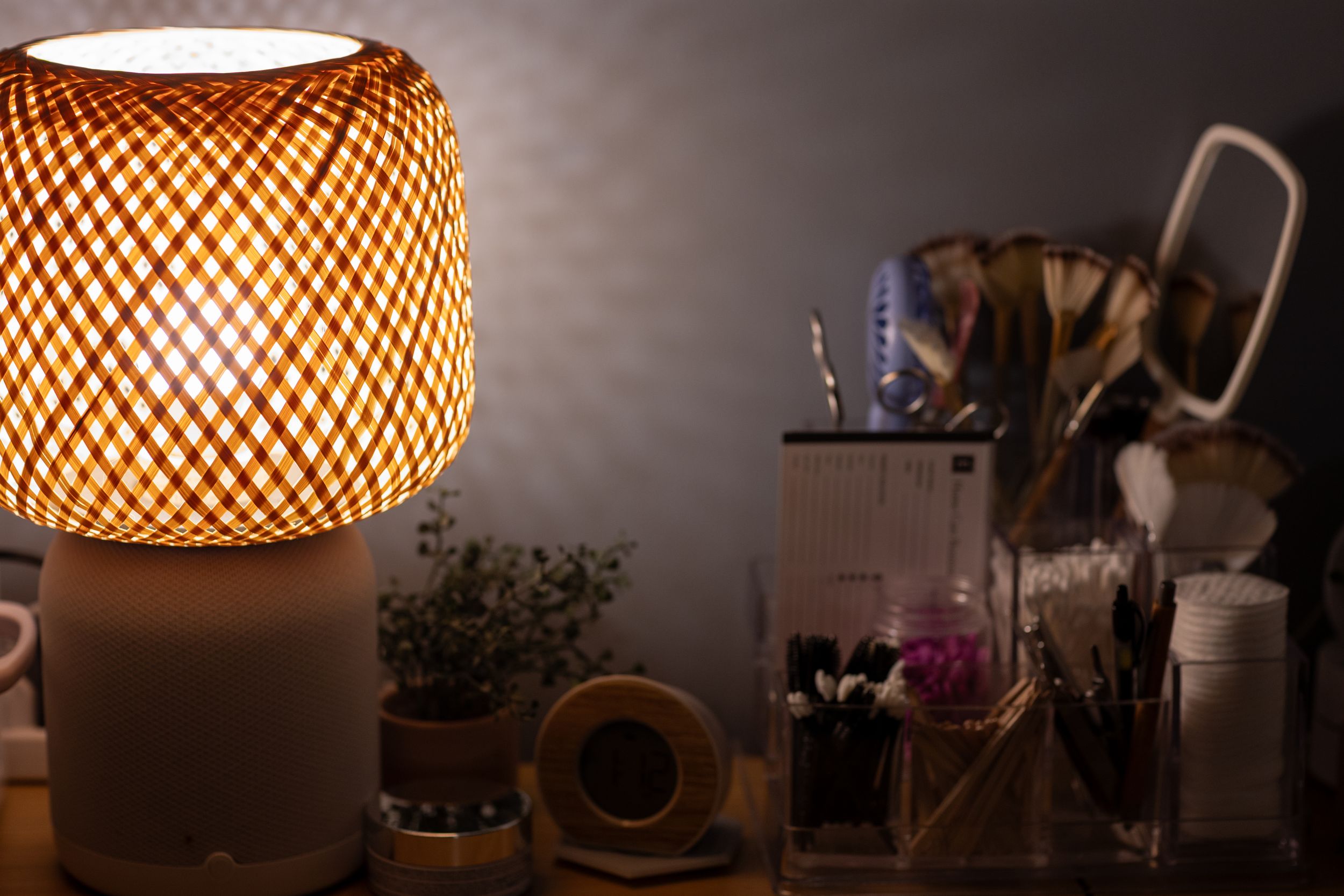 A warm glowing bamboo lamp illuminates a desk with office supplies and dried flowers in a cozy evening setting.