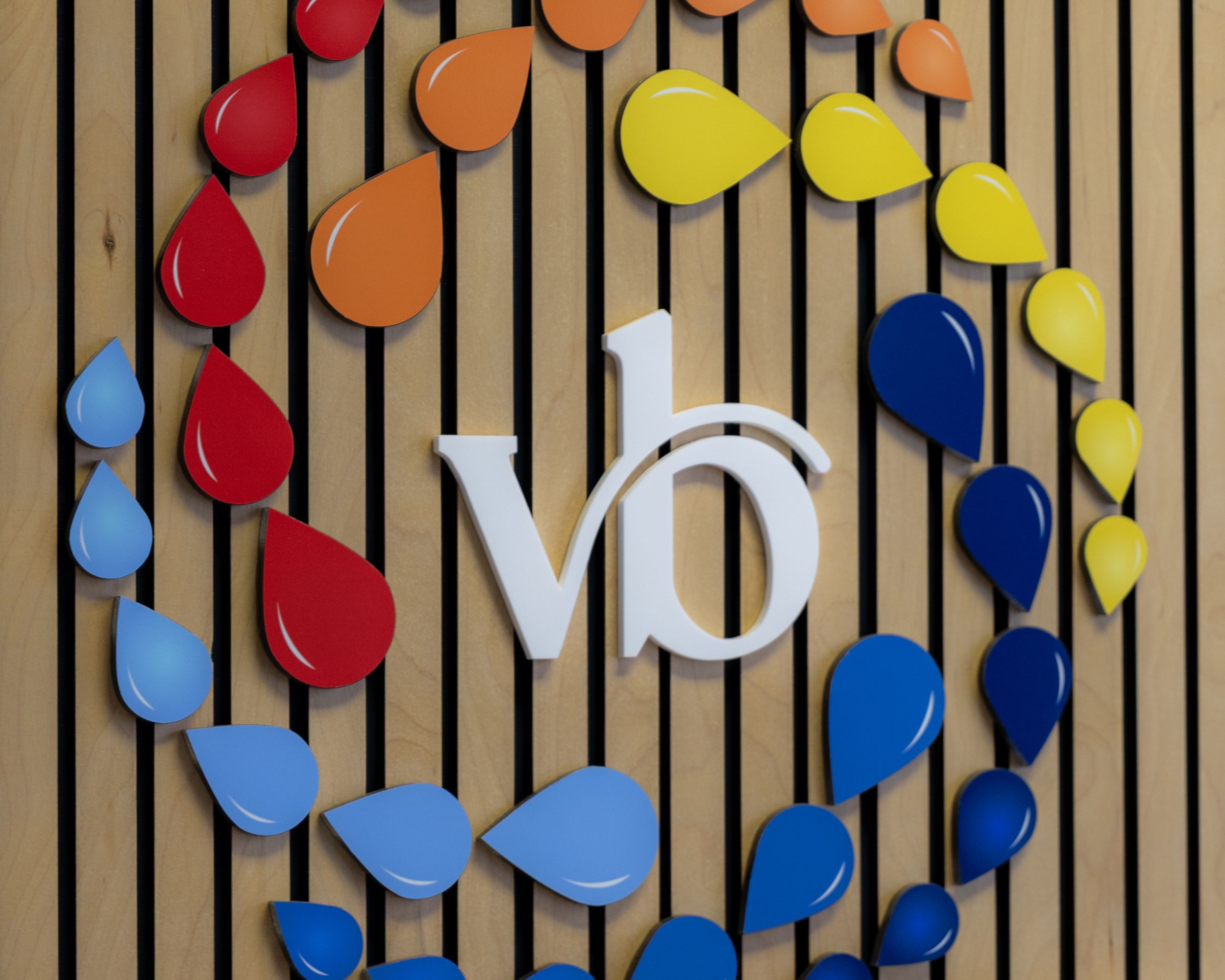 Colorful circular magnets arranged in a pattern on vertical wooden slats create a vibrant display.