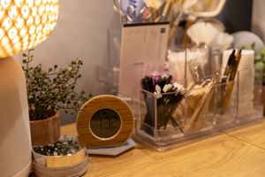 Cozy desk setup with wooden clock, potted plants, and decorative items illuminated by warm lighting.