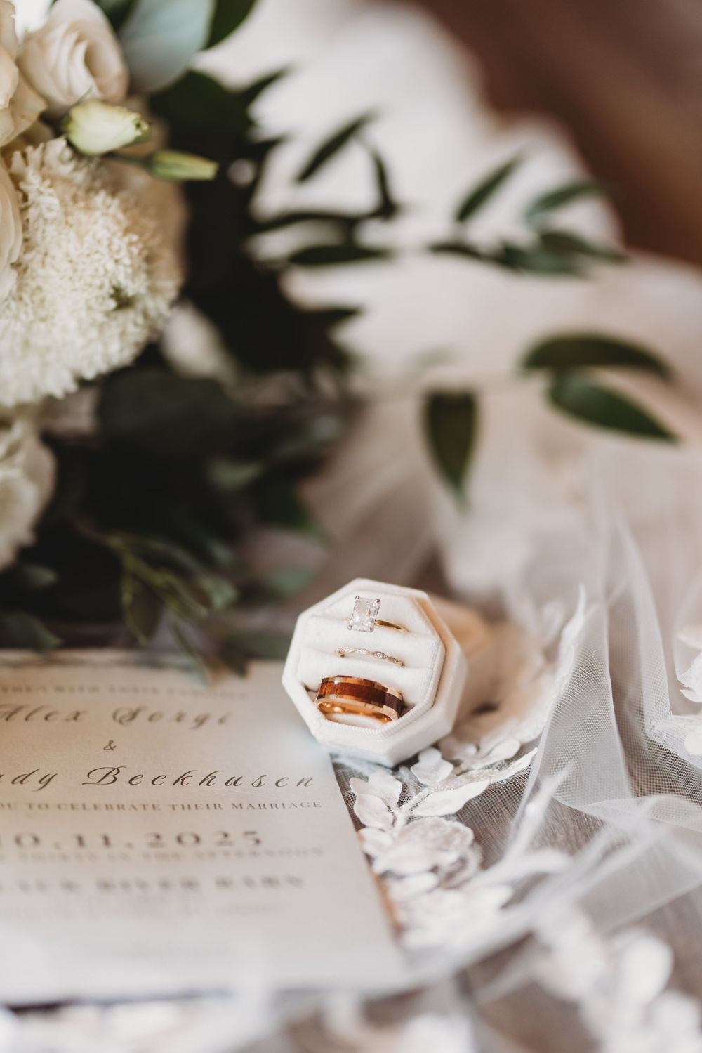 Wedding details featuring delicate floral arrangements and invitation cards arranged with elegant white fabric.