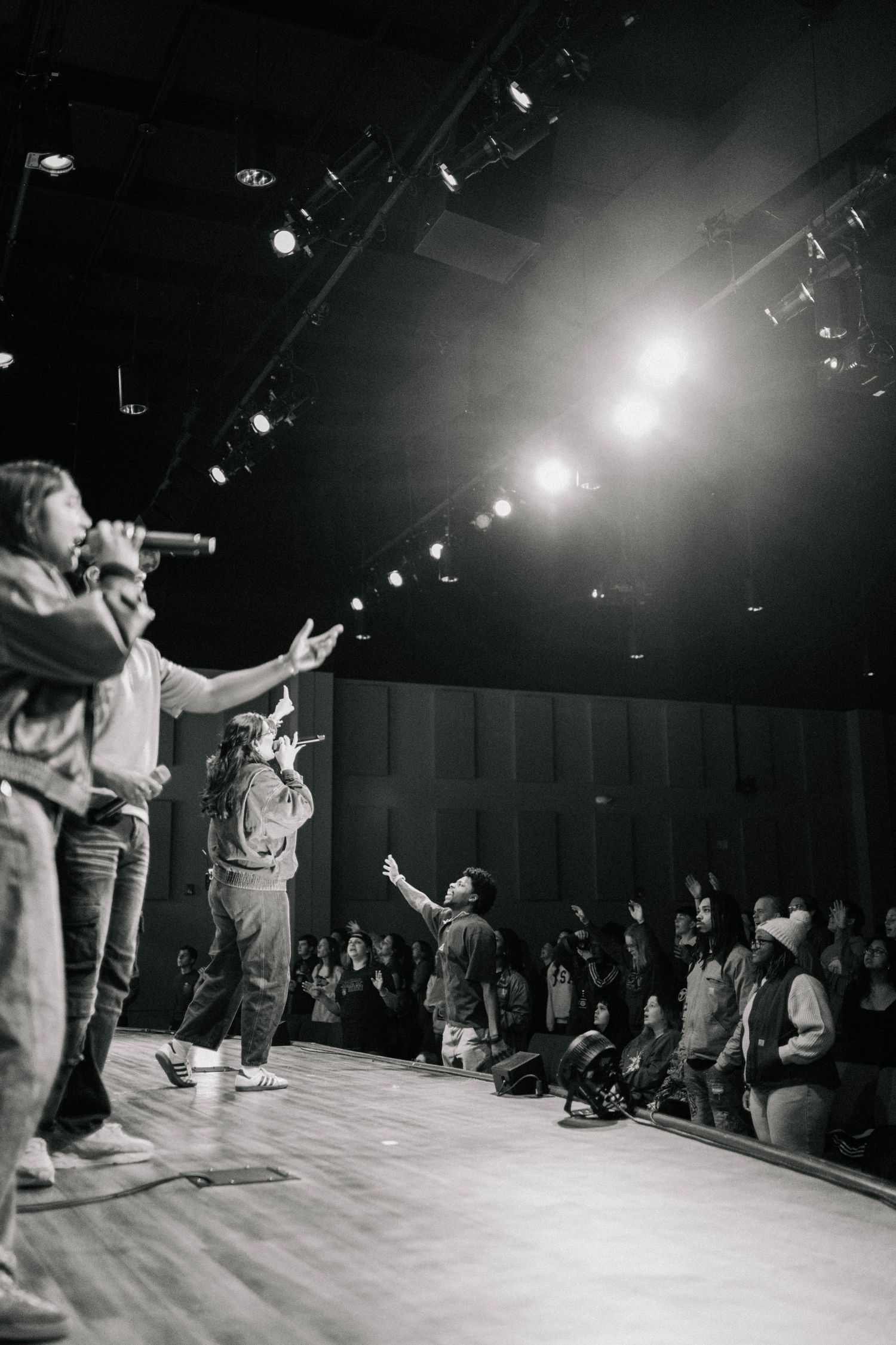singers on a stage singing to a crowd in black and white