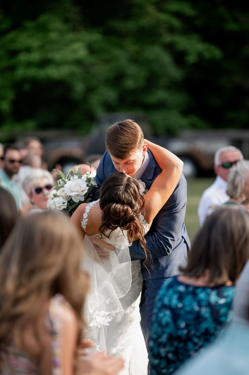 Wedding celebration moment captured with guests in background during outdoor reception.