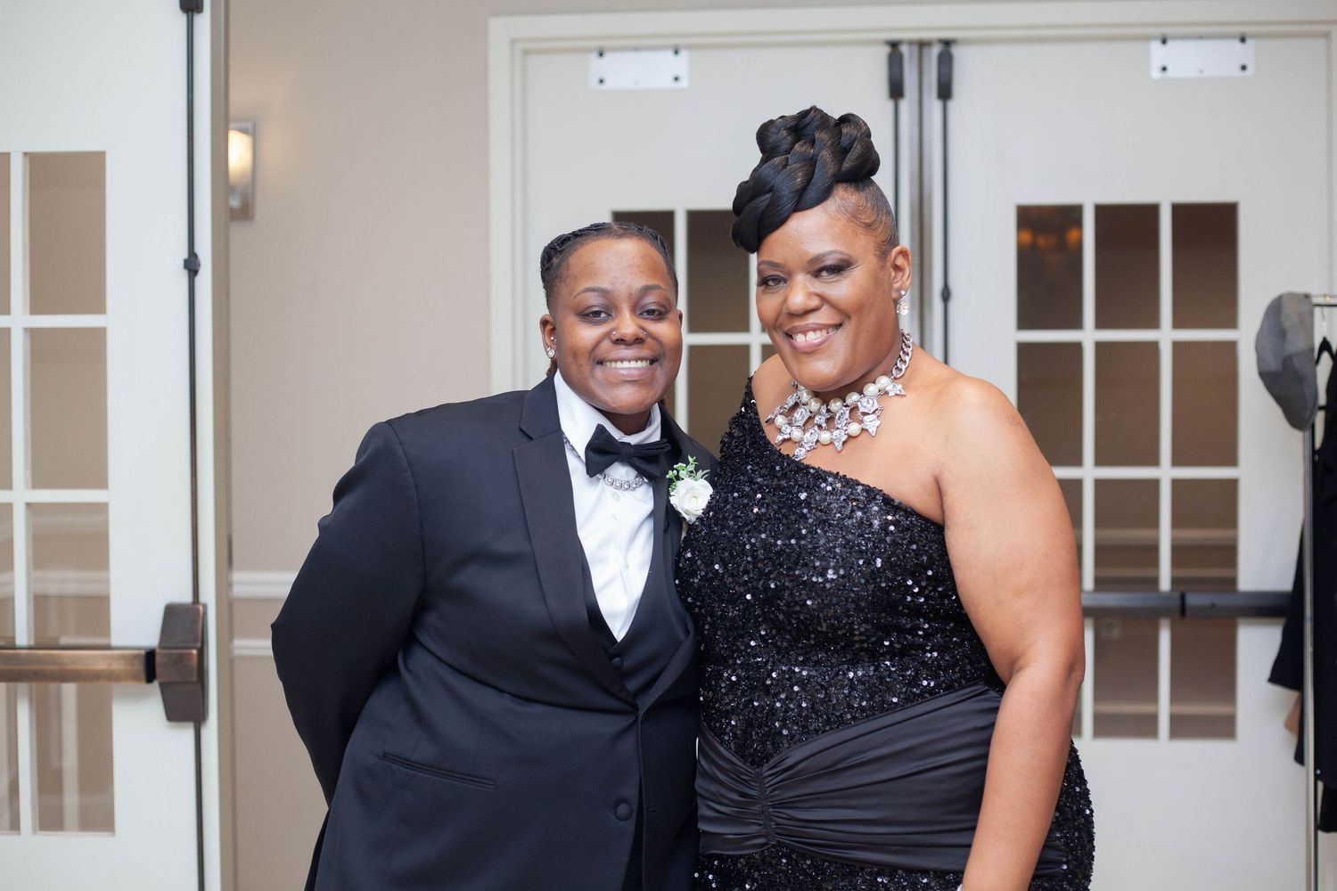A couple in formal attire shares a joyful moment at an elegant indoor venue during a special occasion.