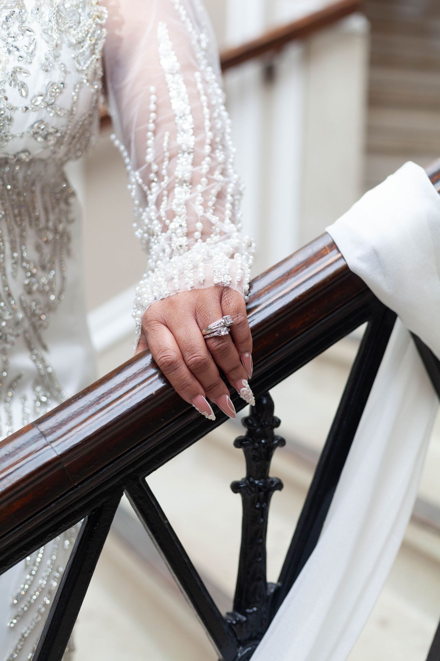 A close-up sequence showing hands in white lace touching an ornate wooden banister or railing.
