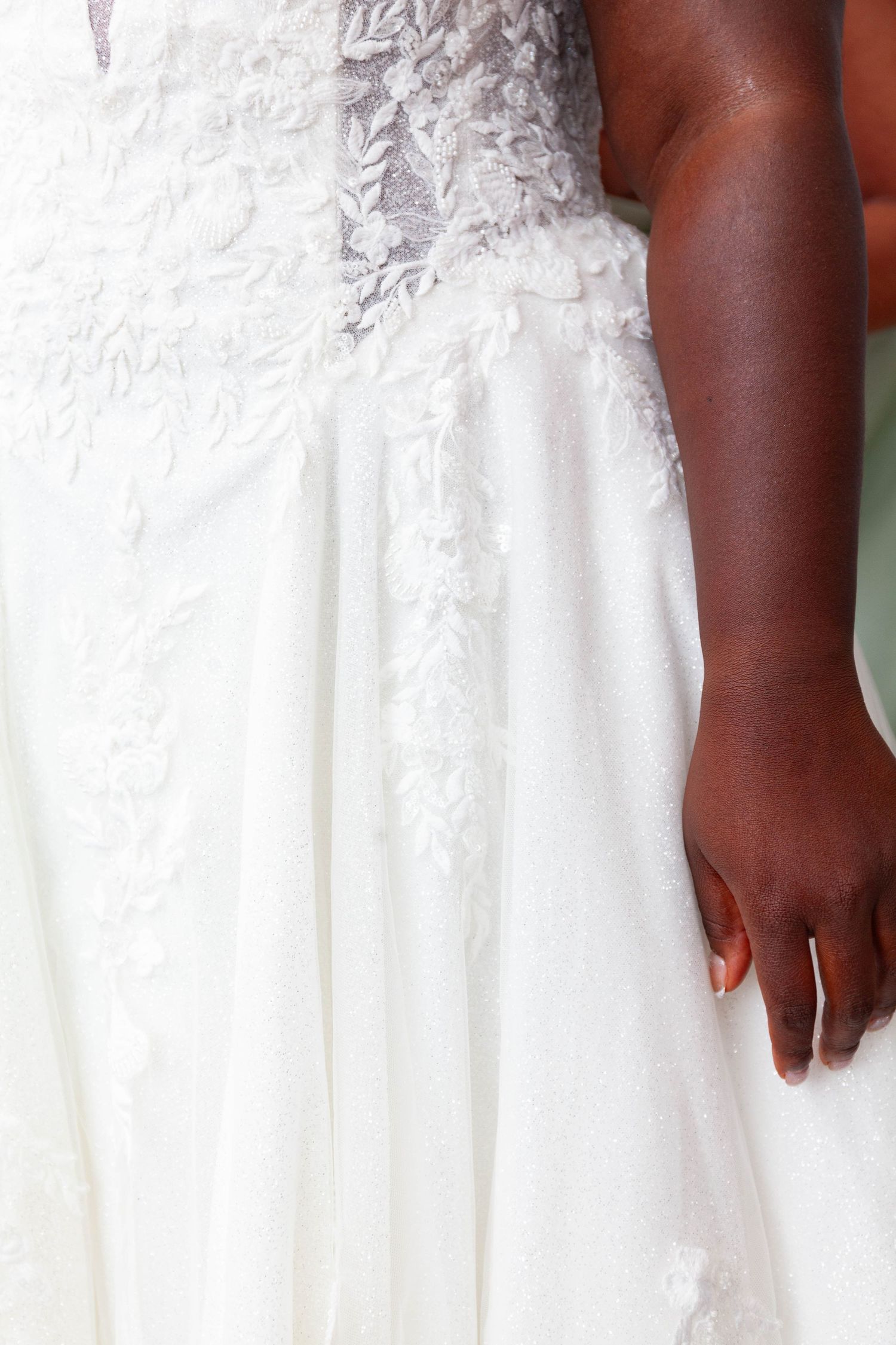 Close-up of a Black bride wearing an elegant white lace wedding gown with floral embroidery detailing.