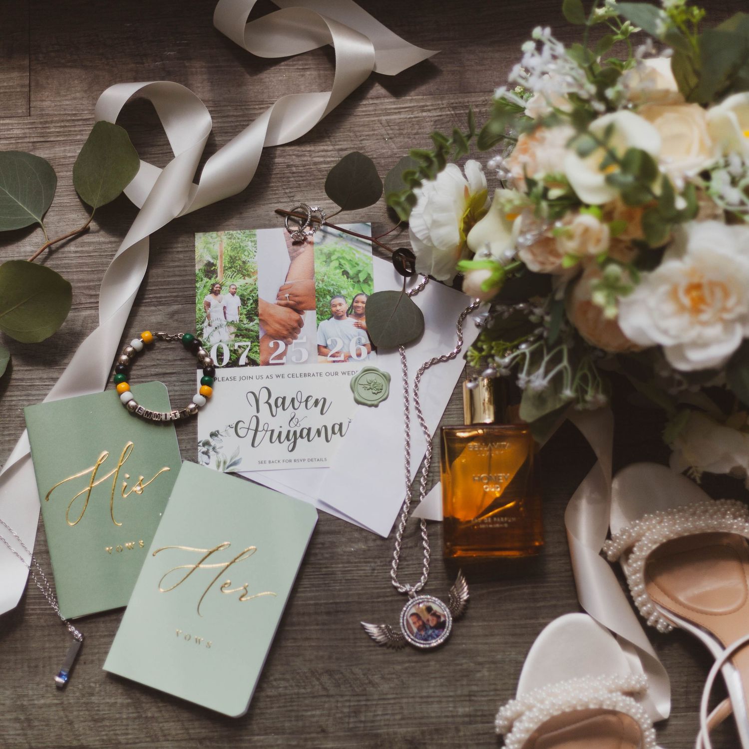 Wedding flat lay with sage green journals, floral bouquet, perfume, jewelry, and invitation for Raven and Arjuna.