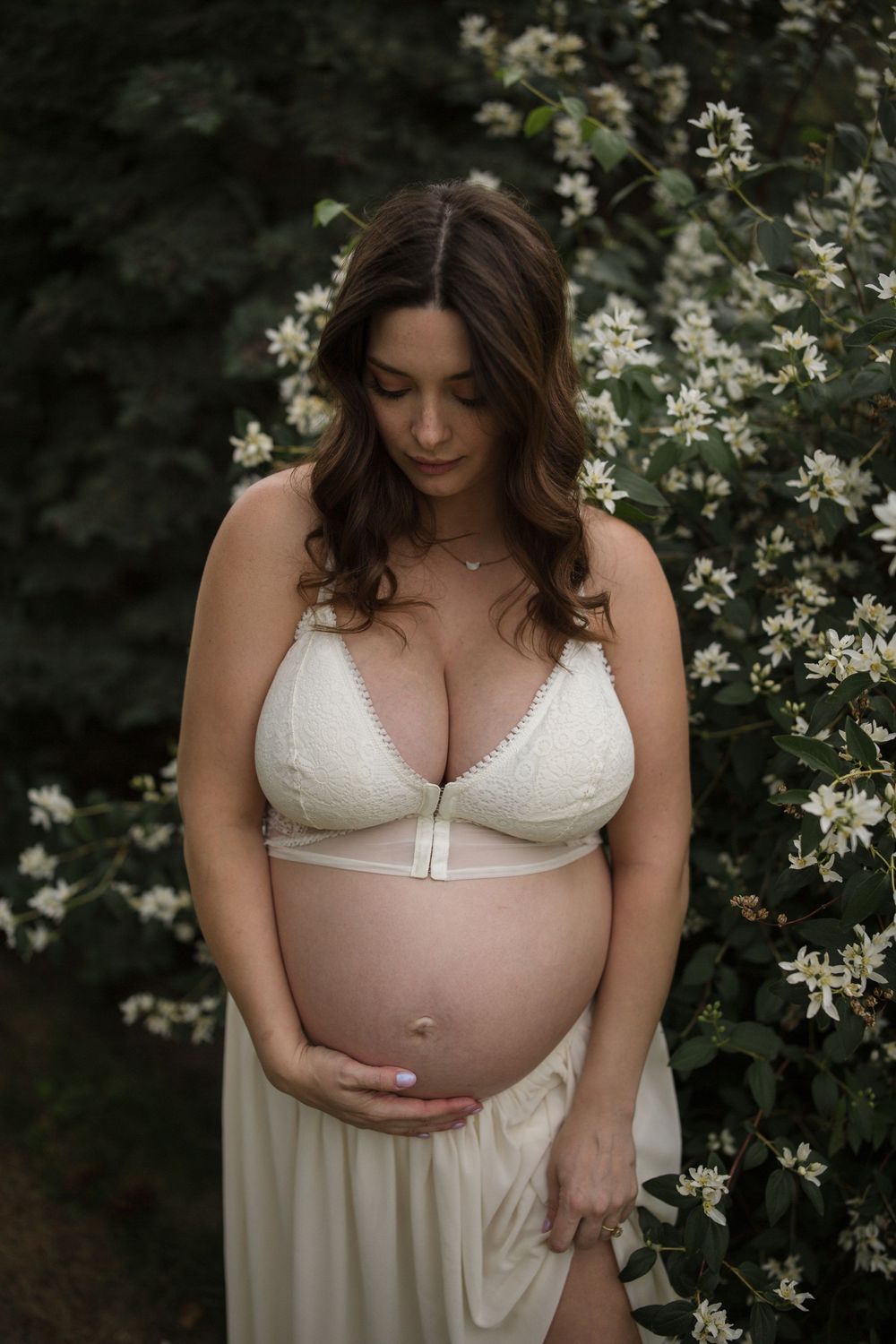 Expecting mother photographed among blooming white flowers during a South Okanagan maternity photography session.