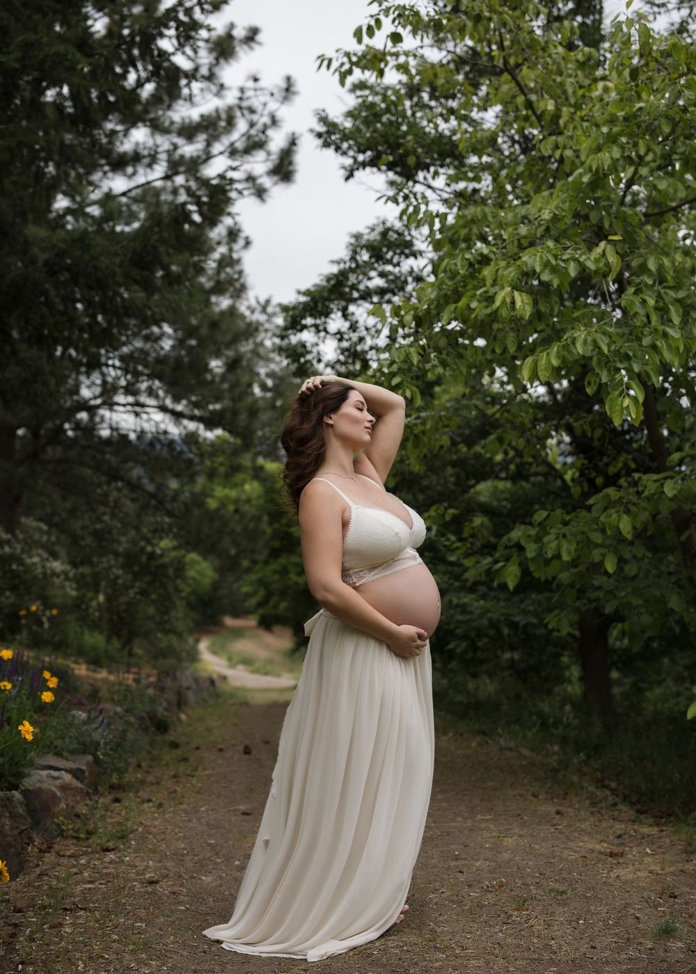 Outdoor maternity portrait featuring an expectant mother in a flowing cream gown in the South Okanagan.