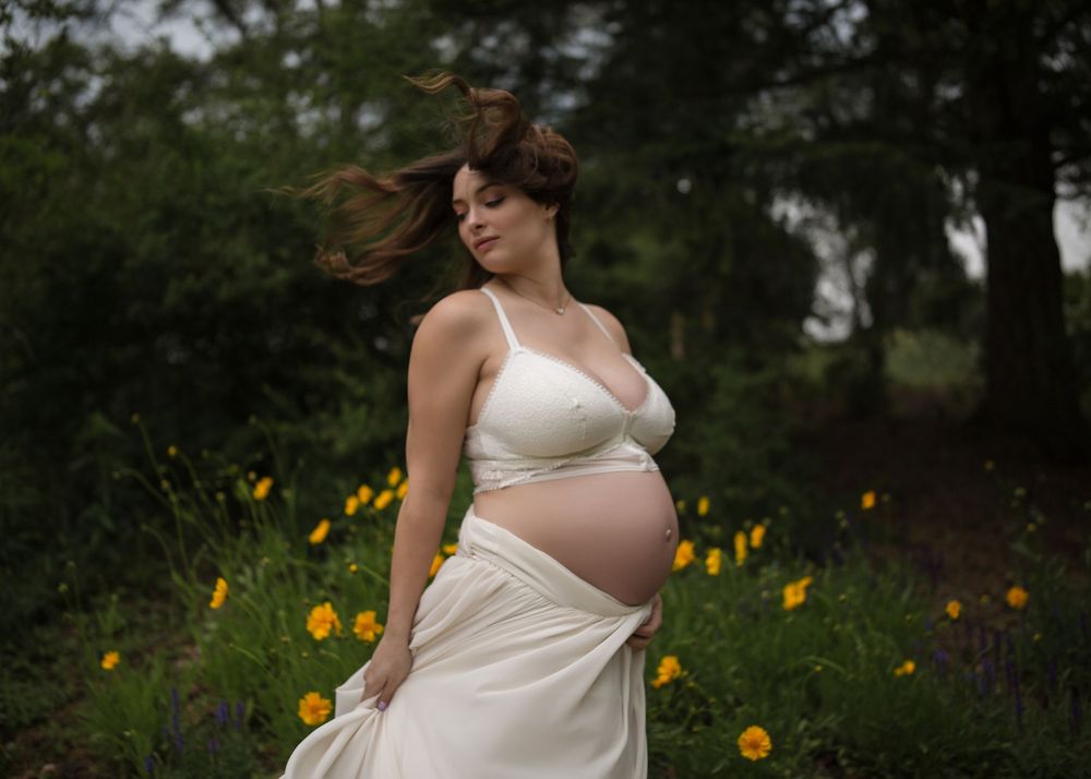 Outdoor maternity portrait of an expecting mother in a flowing cream gown surrounded by wildflowers in the South Okanagan.