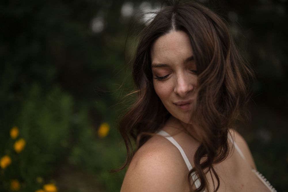 Maternity portrait of an expecting mother surrounded by blooming white flowers during an outdoor maternity session in the South Okanagan.