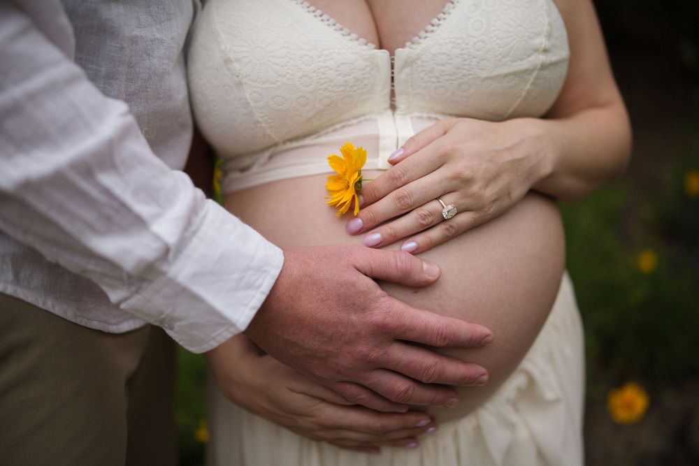 Maternity portrait of an expecting mother surrounded by blooming white flowers during an outdoor maternity session in the South Okanagan.