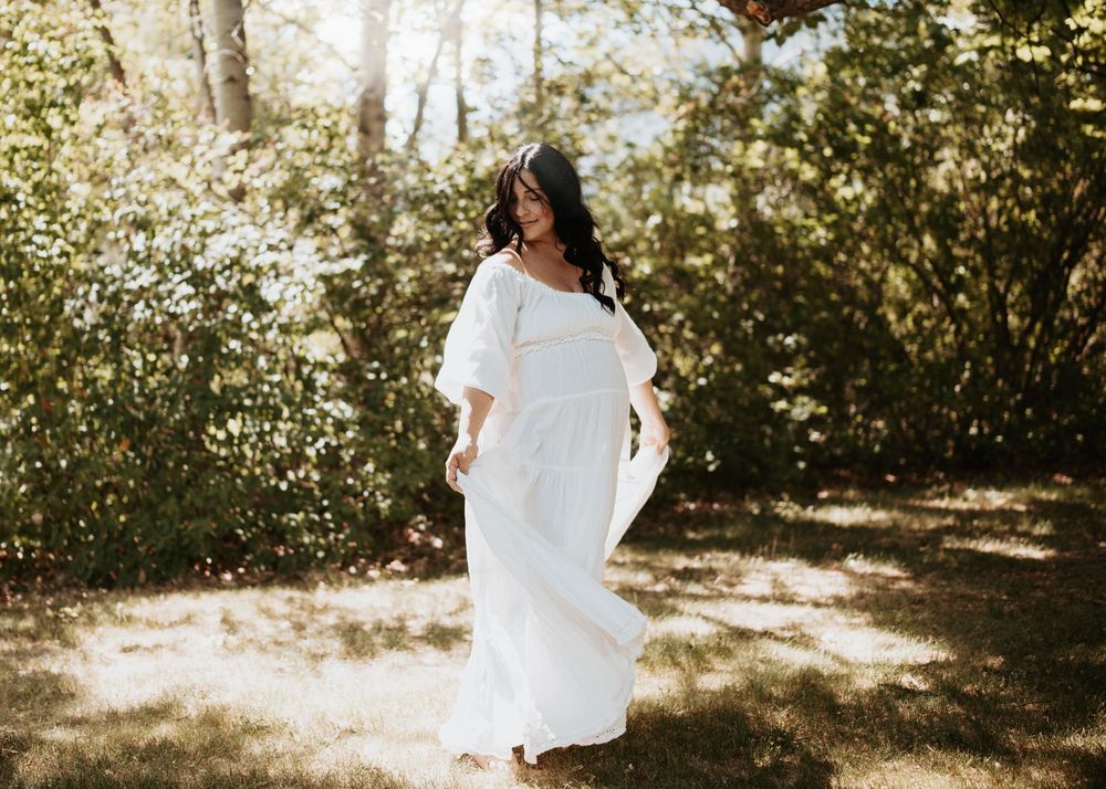 Outdoor maternity portrait of an expecting mother in a flowing cream gown surrounded by wildflowers in the South Okanagan.